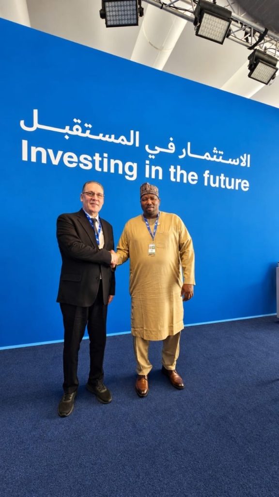 Poignée de main à l'issue de l'entretien, devant le mur « Investing in the future » du WIF 2026 à Doha